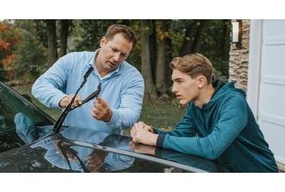 Two men replace a windshield wiper blade