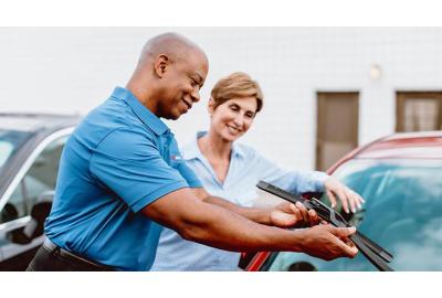 Two people changing the wiper blades on their car