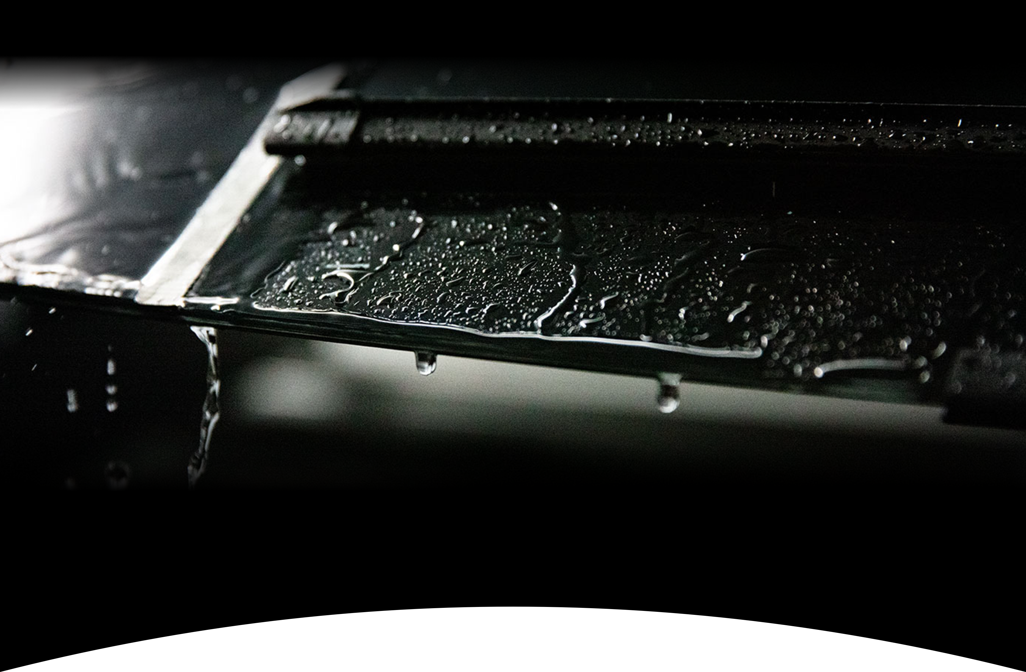 A rain soaked windshield and wiper blade